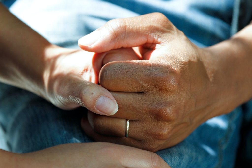 Holding a hospital patient's hand in a medical setting. 